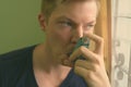 Young handsome man using asthma inhaler at home Royalty Free Stock Photo