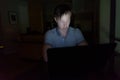 Young handsome man using laptop in the dark living room Royalty Free Stock Photo