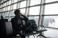 Portrait of young handsome man wearing casual style clothes sitting on the bench in modern airport using smartphone Royalty Free Stock Photo