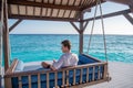 Portrait of young handsome man wearing shirt sitting on sofa near water villas at the tropical beach at island luxury resort Royalty Free Stock Photo