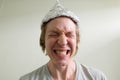 Face of stressed young man with tin foil hat getting scared inside the room Royalty Free Stock Photo