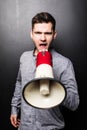 Portrait of young handsome man yelling into the megaphone over black background Royalty Free Stock Photo