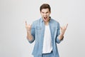 Portrait of young handsome musician screaming and making rock gesture with both hands while enjoying concert. Emotions Royalty Free Stock Photo