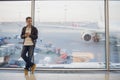Portrait of young handsome person wearing casual style clothes standing near window in modern airport terminal. Traveler