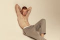 Portrait of young handsome red-haired man posing shirtless in pants isolated over grey studio background. Male beauty Royalty Free Stock Photo