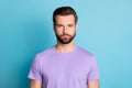 Portrait of young handsome serious reliable male look camera wear violet t-shirt isolated on blue color background