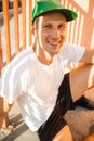 Portrait of young handsome sport man in green cap and white T-shirt smiling to camera outdoor Royalty Free Stock Photo