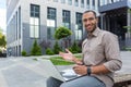 Portrait of young happy African American man, student outside campus smiling and looking at camera, teacher using laptop Royalty Free Stock Photo