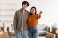 Portrait of young happy Asian couple holding house key, posing in apartment with carton boxes. Moving day concept Royalty Free Stock Photo