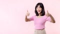 Portrait young happy asian woman cheerful smile showing thumb up, trust, recommend gesture isolated on pink pastel studio Royalty Free Stock Photo