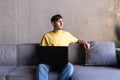 Portrait of young happy man smiling and using laptop while sitting on sofa at home Royalty Free Stock Photo