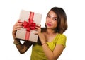 Portrait of young happy and beautiful Asian Indonesian woman holding Christmas present or birthday gift box with red ribbon Royalty Free Stock Photo