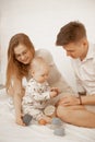 Portrait of young beautiful family sitting with little cute plump infant baby playing with modern pastel silicone bowls.