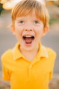 Portrait of young happy boy smiling and screaming cute boy in yellow shirt at sunset background close up Royalty Free Stock Photo