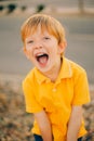 Portrait of young happy boy smiling and screaming cute boy in yellow shirt at sunset background close up Royalty Free Stock Photo