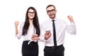 Portrait of young happy business colleagues couple isolated over white wall background using mobile phones make winner gesture Royalty Free Stock Photo