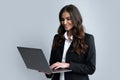 Portrait of a young happy business woman with a laptop over gray background. Royalty Free Stock Photo