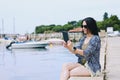 Portrait of young happy business woman relaxing, working in city, beach at Adriatic seaside. Using laptop. Selfie. Technology.