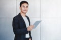 Portrait of Young Happy Businessman Using Digital Tablet. Standing by the Industrial Concrete Wall