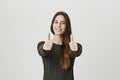 Portrait of young happy european girl showing her thumbs up in approving gesture looking cheerful, isolated over white Royalty Free Stock Photo