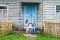Portrait of young happy family with baby kid in baby carriage sitting together in front of old retro wooden house Royalty Free Stock Photo