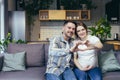 Portrait of a young happy family. Husband and pregnant woman waiting for the birth of a child sitting on the couch at home, Royalty Free Stock Photo