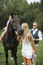 Portrait of a young happy family, parents and children, having fun at countryside outdoors, walking with horse. Kids are Royalty Free Stock Photo