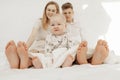 Portrait of young happy family with upset frowning little baby infant toddler sitting resting on bed, showing bare feet. Royalty Free Stock Photo