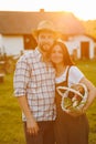 Portrait of young happy farmer couple holding basket with fresh organic vegetables on their rancho at the sunset Royalty Free Stock Photo