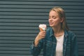 Portrait of young happy girl eating ice-cream, outdoor, over blue wall background Royalty Free Stock Photo