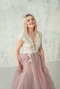 Young happy girl in an evening dress with lace and pink fartine on the background of a white textural wall. Close up Royalty Free Stock Photo