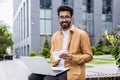 Portrait of young happy Hindu man, student outside campus smiling and looking at camera, teacher using laptop for online Royalty Free Stock Photo