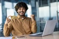 Portrait of a young happy Indian man working in the office at a laptop, holding a credit card in his hand to the camera Royalty Free Stock Photo