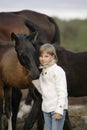 Portrait of a young happy little girl in white sweater and jeans with foal. Lifestyle Royalty Free Stock Photo