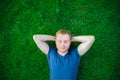 Portrait of a young happy man with closed eyes relaxing on the grass with his hands under the head. Selective focus. Royalty Free Stock Photo