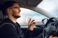 Portrait of young happy man, explaining something and driving the car. Wearing eyeglasses. Royalty Free Stock Photo