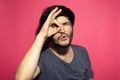 Portrait of young happy man, looking at camera through ok gesture, copy space concept on background of coral pink. Royalty Free Stock Photo