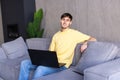 Portrait of young happy man smiling and using laptop while sitting on sofa at home Royalty Free Stock Photo