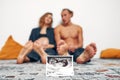 Portrait of young happy married couple hold ultrasound picture. Cheerful family and ultrasound scan photo. Concept of