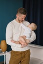 Portrait of a young happy man holding his cute baby in his arms. Caucasian father gently hugs his charming little son and smiles. Royalty Free Stock Photo