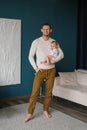 Young happy man holding his cute baby in his arms. Caucasian father gently hugs his charming little son and smiles. Shooting in a Royalty Free Stock Photo