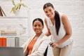 Portrait of a young happy mixed race businesswoman helping a colleague in a wheelchair to her office at work. Content Royalty Free Stock Photo