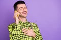 Portrait of young happy positive laughing man talking on phone hear funny news isolated on purple color background