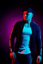 Portrait of a young happy serious man at studio. High Fashion male model in colorful bright neon lights posing on black Royalty Free Stock Photo