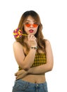 Portrait of young happy and Asian Korean girl in cool fashion sunglasses eating lollipop candy posing naughty teasing Royalty Free Stock Photo