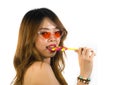 Portrait of young happy and Asian Korean girl in cool fashion sunglasses eating lollipop candy posing naughty teasing Royalty Free Stock Photo