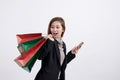 Portrait of young happy smiling Asian woman with shopping bags and smart phone Royalty Free Stock Photo