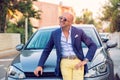 Smiling attractive man in business suit sitting near his new stylish car outdoor Royalty Free Stock Photo