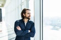 Portrait of young happy smiling business man with crossed hands standing near panoramic window Royalty Free Stock Photo