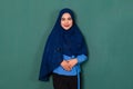 Portrait of young happy smiling confident beautiful Muslim woman dressed nicely wearing blue hijab standing and looking to a Royalty Free Stock Photo